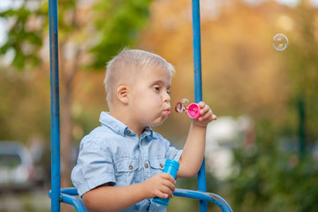 A boy with Down syndrome blows soap bubbles. Chromosomal and genetic disorder in the baby.