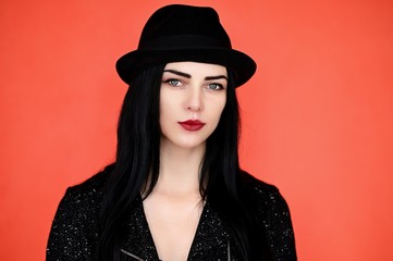 Concept close-up portrait of a pretty brunette girl in a hat on a colorful background in the studio.