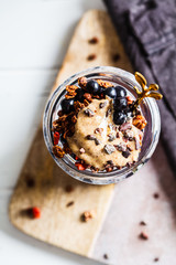 Chia pudding with berries, granola and peanut butter in jar, top view. Healthy vegan breakfast.