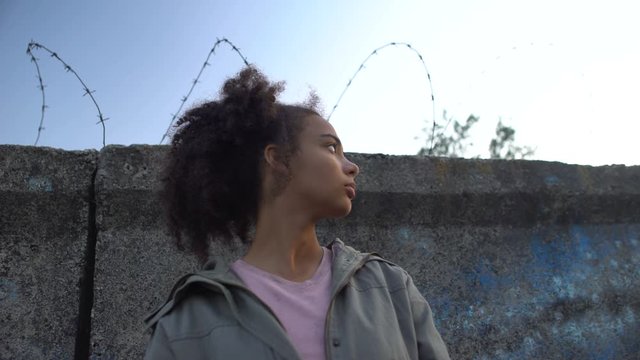 Teen girl looking at barbed wire dreaming to escape prison, juvenile delinquency
