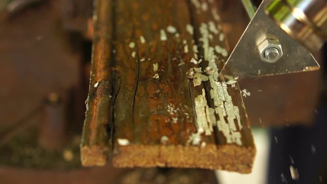 worker using a building hair dryer heats paint on a wooden bar and cleans it with a scraper, slow motion, close-up