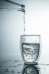 Fresh and cold, pure Water is poured into a glass. Purified water in a glass on a gray background....