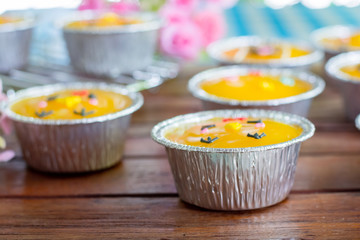 Close up minimal orange cake with butter cream in foil cup on wooden table. Delicious bakery in coffee and tea times