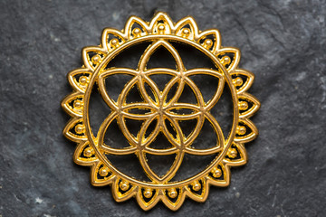 Sacred geometry flower of life metal jewelry component on neutral background, seed of life
