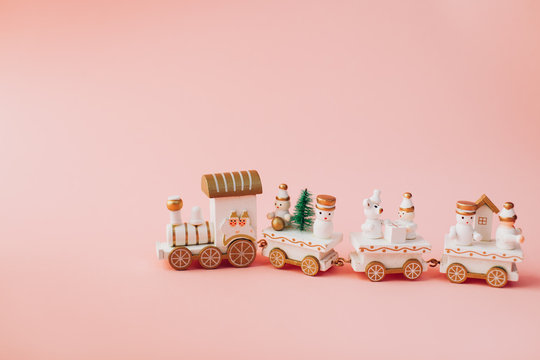 holiday concept.  Christmas and New Year.  postcard.  small toy miniature train with Santa, snowman, Christmas tree, on a pink background in isolation