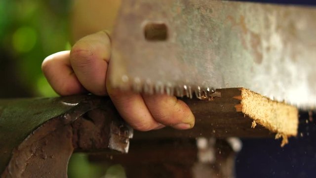Carpenter cuts part of a wooden bar with a hand saw, slow motion, closeup