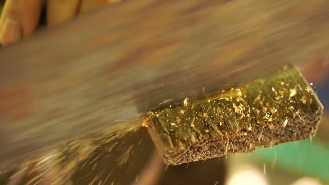 Carpenter cuts part of a wooden bar with a hand saw, slow motion, closeup