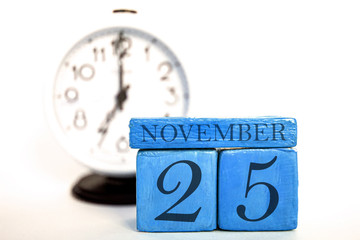 november 25th. Day 25 of month, handmade wood calendar and alarm clock on blue color. autumn month, day of the year concept