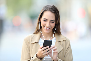 Front view portrait of a happy girl listening to music