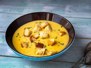 Homemade soup-puree of vegetables on mushroom broth with croutons in a deep dish on a Board table