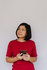 Happy woman is thinking with smartphone on white background