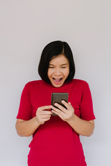 Surprised happy woman looking at the smartphone on white background