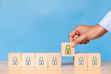 Businessman hold wooden cube with choose human icon on blue background. Concept of human resources management and recruitment business