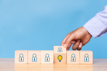 Hand flip wooden cube with human icon to light bulb on blue background. Concept of Idea, solution and creative