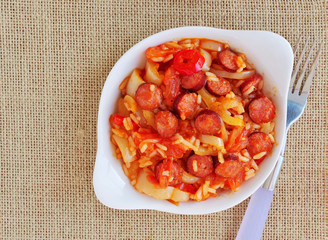 Vegetable stew with spicy sausage and rice in white bowl over burlap background. Hungarian bell...