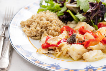 cod fish with quinoa and fresh salad on dish