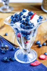 Muesli with yogurt and berries in a glass goblet on a wooden table