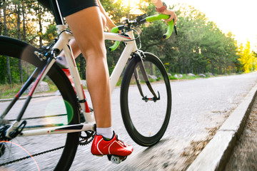 Fototapeta premium Young Woman Cyclist Riding Road Bicycle on the Free Road in the Forest at Hot Summer Day. Healthy Lifestyle Concept.