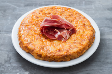 typical spanish food Tortilla with smoked meat and potato on white dish