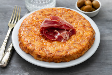typical spanish food Tortilla with smoked meat and potato on white dish