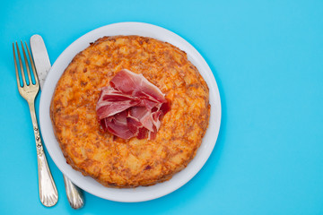 typical spanish food Tortilla with smoked meat and potato on white dish
