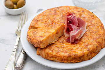 typical spanish food Tortilla with smoked meat and potato on white dish