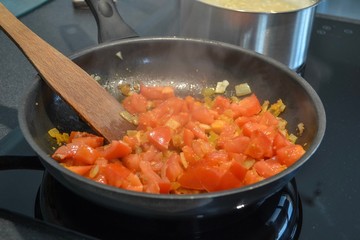 Homemade cooking. Frying onions and tomatoes in a pan
