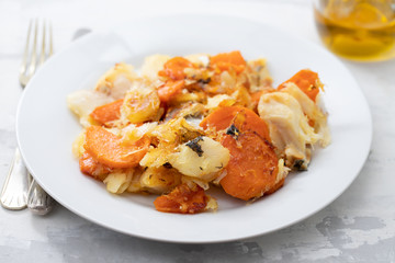 fried cod fish with sweet potato on white dish on ceramic background