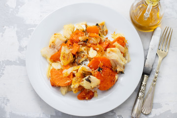 fried cod fish with sweet potato on white dish on ceramic background