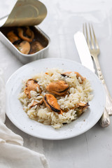 rice with mussels on small white plate on ceramic background