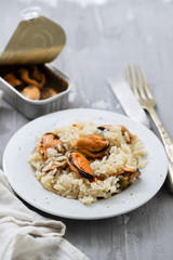 rice with mussels on small white plate on ceramic background