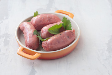 raw sausages on dish on ceramic background
