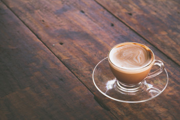 a cup of hot coffee in a glass coffee cup on old wood table 