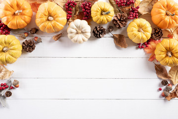 Top view of Autumn maple leaves with Pumpkin and red berries on white wooden background. Thanksgiving day concept.