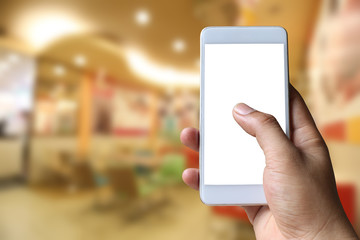 Hand of a man holding smart phone device in the coffee cafe background.