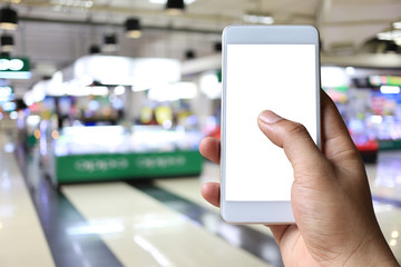Hand of a man holding smartphone device in the Shopping mall background.