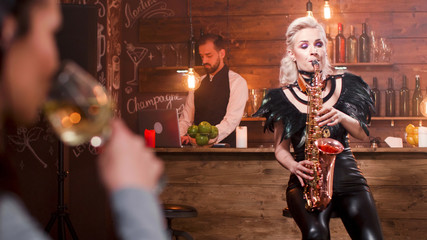 Young woman playing on saxophone in entertainment club