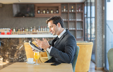 Handsome young businessman reading newspaper in hotel cafe