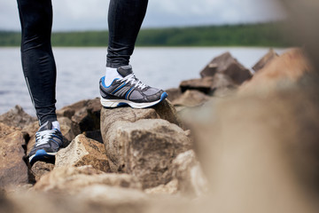 Sportsman feet standing on rocky lake bank