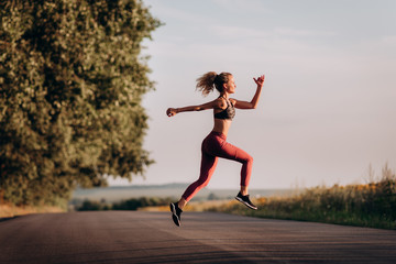 Young woman runner running on city bridge road