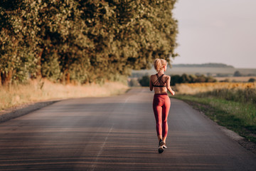 Young woman runner running on city bridge road