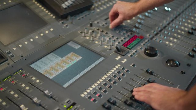 Close-up of hands tune in a mixing console. A sound director works in a studio. A professional recording studio. Voice acting films.