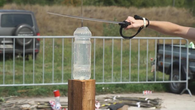 A man cuts a cavalry saber plastic bottle of water. Slow motion