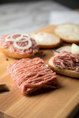 Deutsche Mettbrötchen mit rohen Schweine Mett, Brötchen, Butter, Zwiebeln, Pfeffer und Mett auf Holzbrett mit Messer in Küche