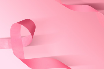 Pink awareness ribbon on a colored background