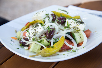 Griechischer Bauernsalat mit Oliven, Peperoni, Feta, Gurke, Tomate und Zwiebeln auf Holz Tisch