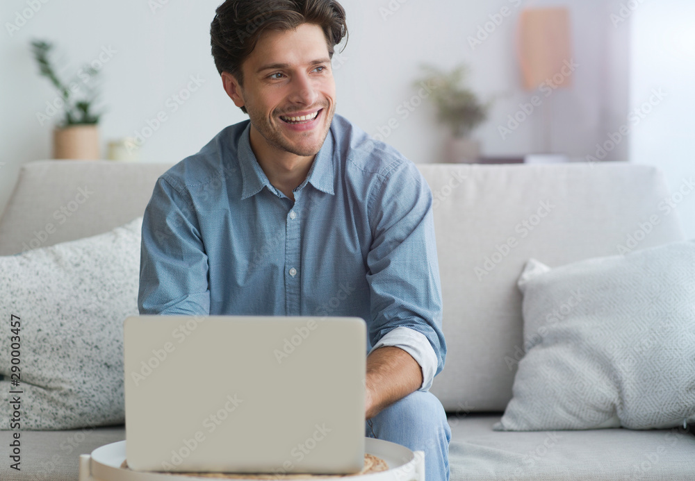 Poster man using laptop making video call sitting on couch