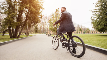 Gas savings concept. Young businessman riding bicycle to work