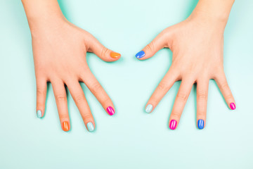 Woman's hands with perfect manicure in trendy neon colors on turquoise background. Beauty concept.