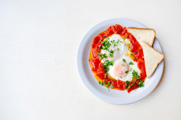 Fried eggs with sliced tomatoes and parsley on the plate. Roasted eggs with copy space, top view. Healthy breakfast and lunch.